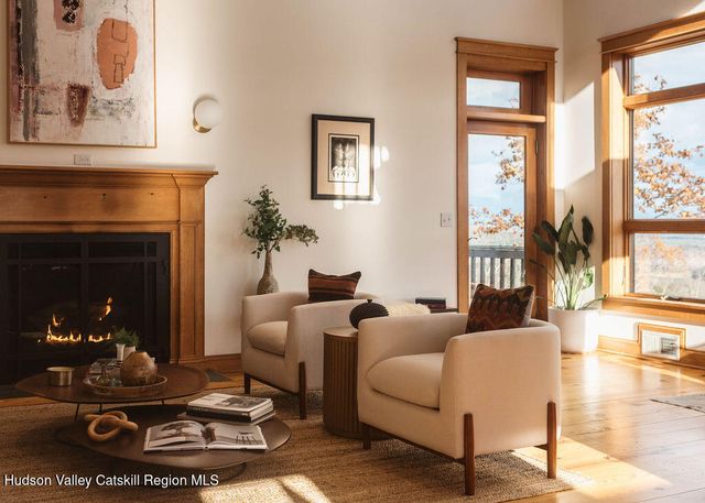 a living room with furniture a fireplace and floor to ceiling windows