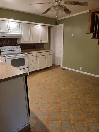 a kitchen with granite countertop a sink a stove top oven and cabinetry