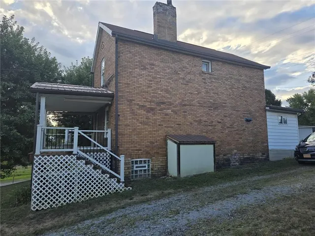 a brick house with a small yard and large trees