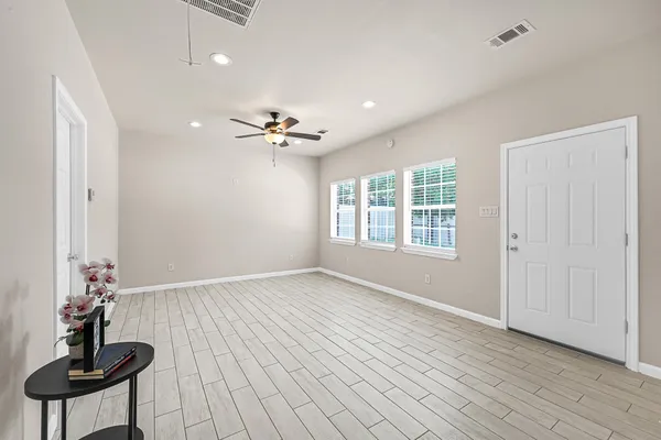 a view of an empty room with a window and wooden floor