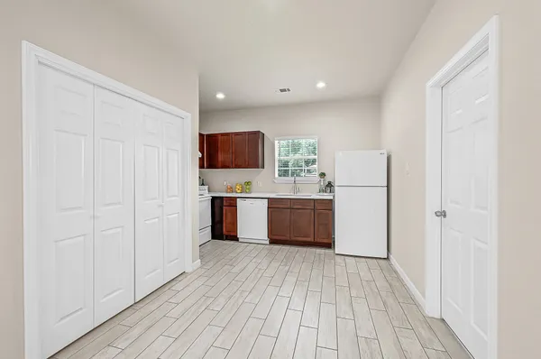 a large white kitchen with a sink and dishwasher a refrigerator with wooden floor
