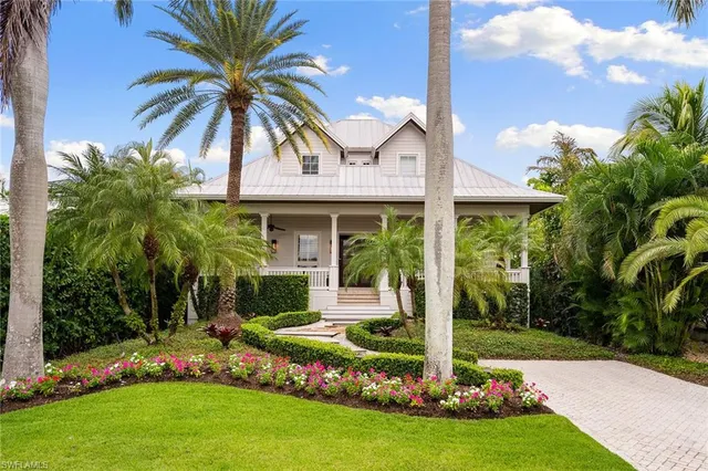 a front view of yellow house with a garden and plants