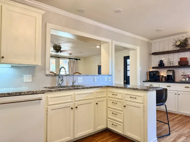 a kitchen with granite countertop white cabinets white appliances and sink