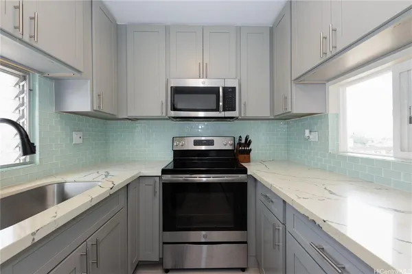 a kitchen with granite countertop a sink a stove and cabinets