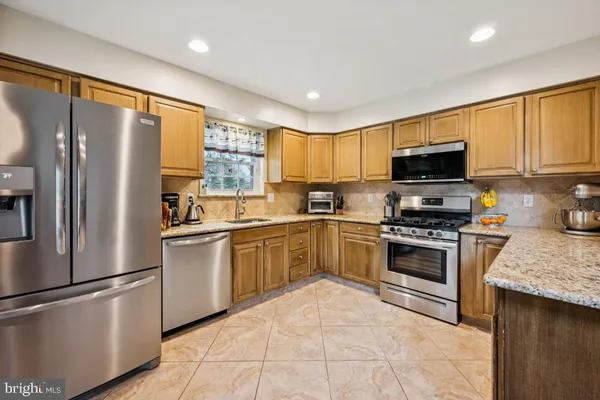 a kitchen with stainless steel appliances granite countertop a refrigerator and wooden cabinets