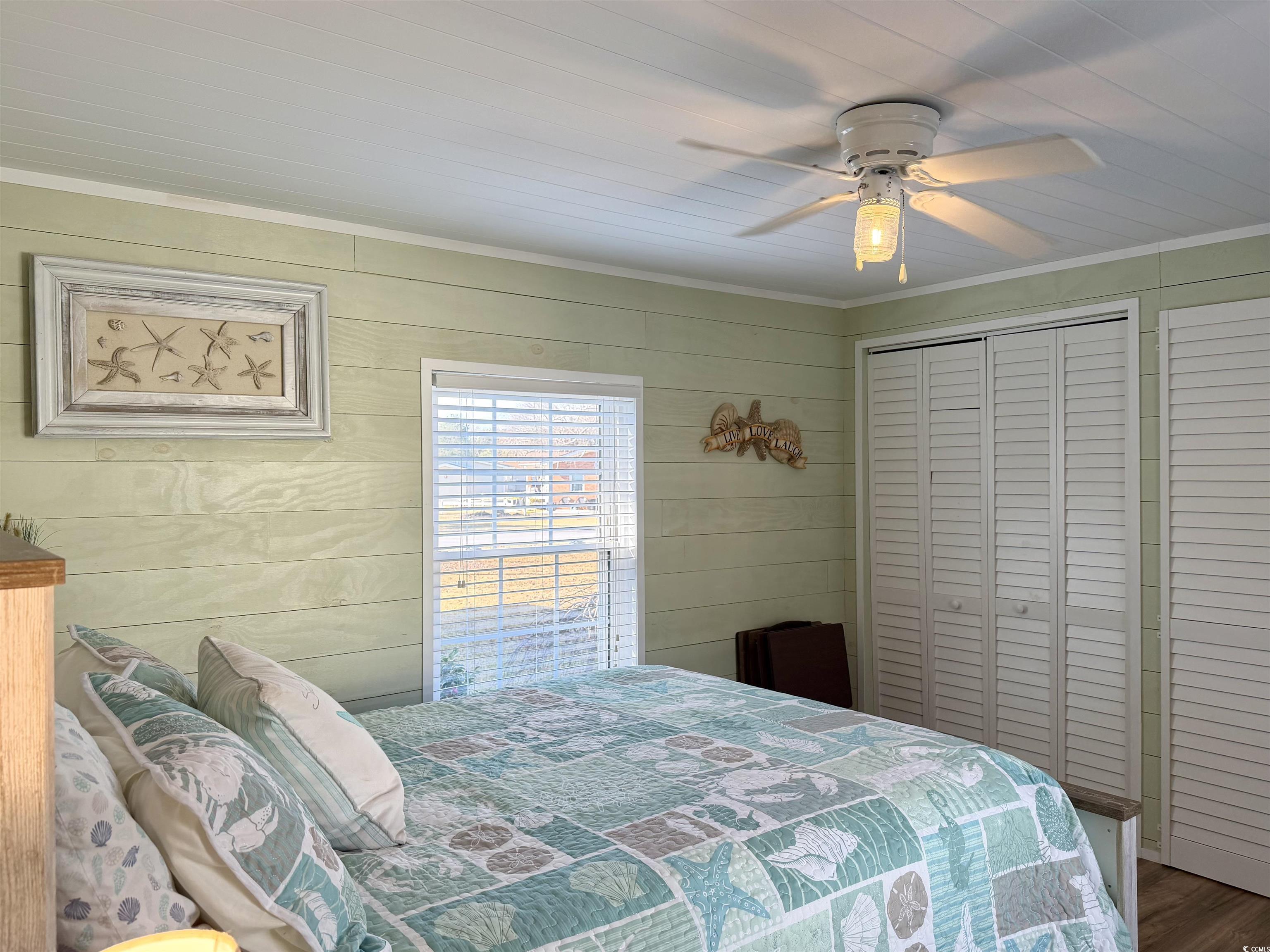 292 Flamingo Surfside Beach, SC 29575 - Photo 11 of 32 Bedroom with a ceiling fan, crown molding, a closet, wood finished floors, and wooden walls