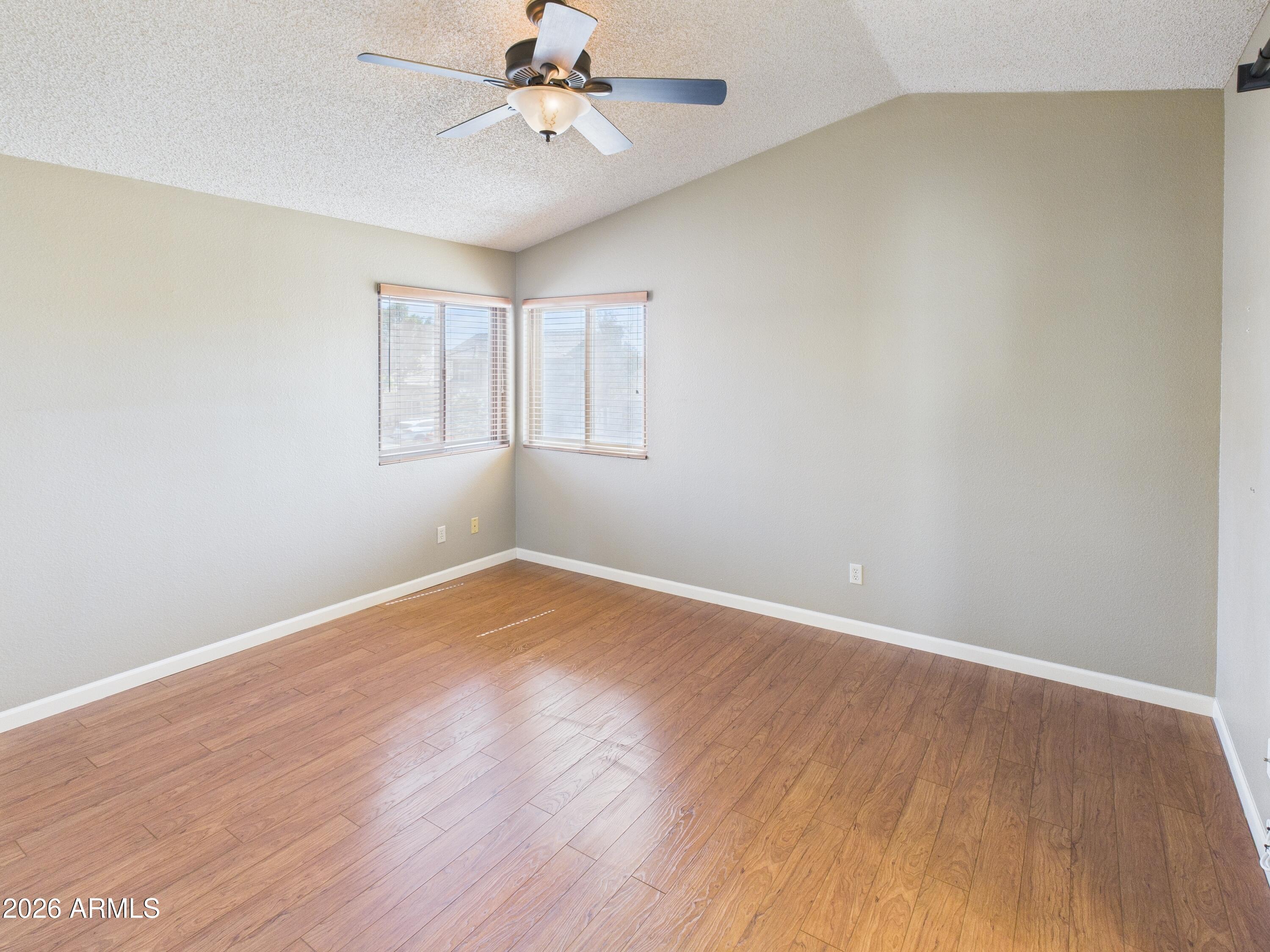 2750 East Rock Wren Road Phoenix, AZ 85048 - Photo 32 of 90 an empty room with wooden floor fan and windows