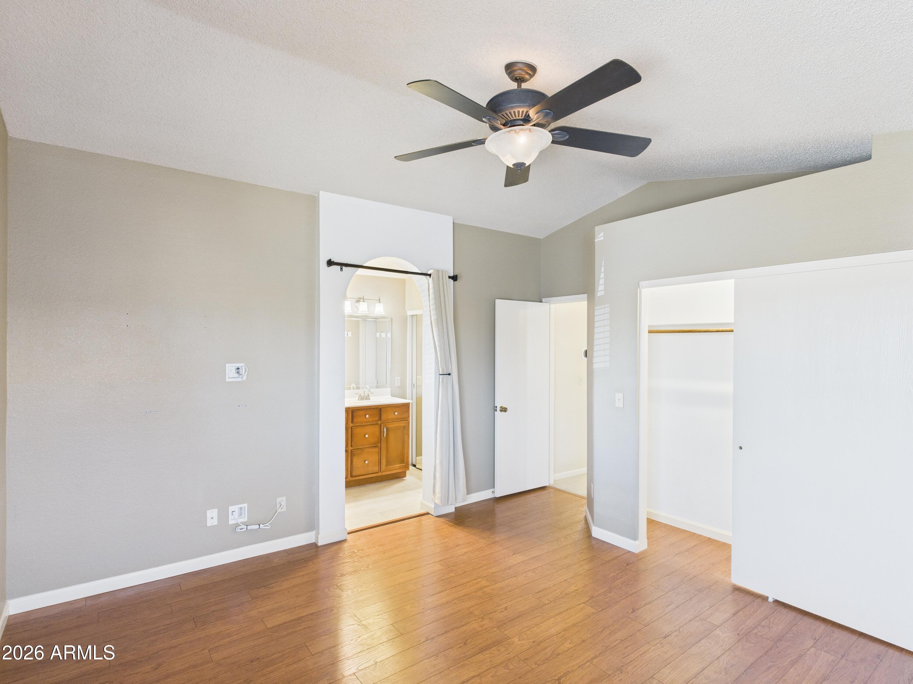 2750 East Rock Wren Road Phoenix, AZ 85048 - Photo 33 of 90 an empty room with wooden floor and a ceiling fan