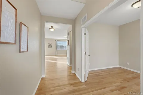 a view of a hallway with wooden floor and bathroom