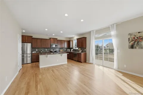a kitchen with stainless steel appliances kitchen island wooden floors granite counter tops and a window