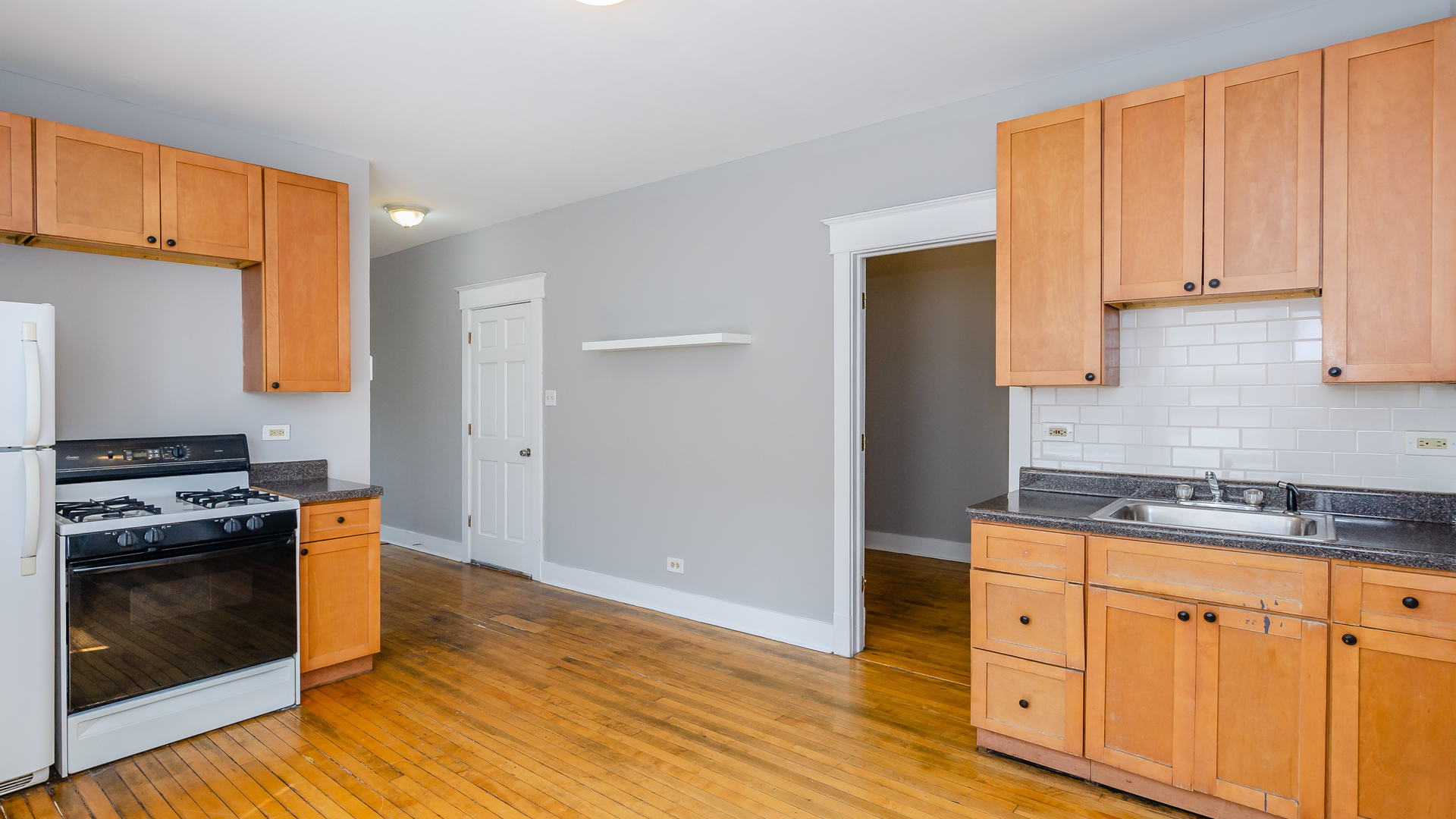 2639 West 25th Street, Unit 2F Chicago, IL 60608 - Photo 2 of 11 a kitchen with granite countertop cabinets stainless steel appliances and wooden floor