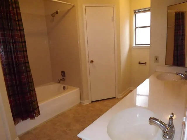 a bathroom with a tub a sink and a large window