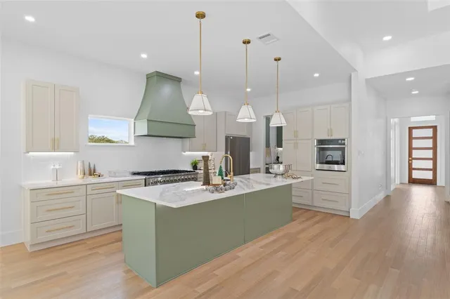 a kitchen with kitchen island granite countertop a sink a stove and a wooden floors