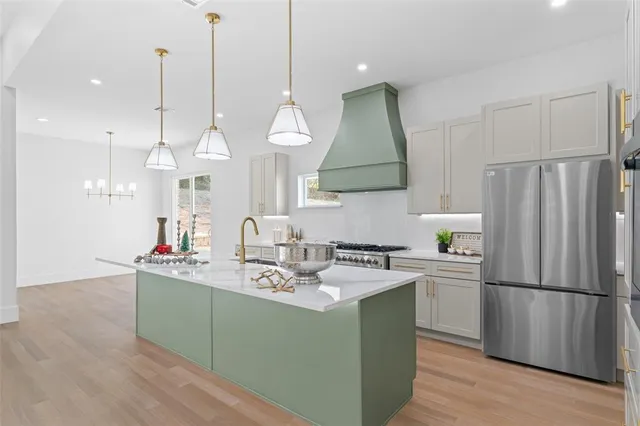 a kitchen that has a sink stainless steel appliances a refrigerator and a counter top space