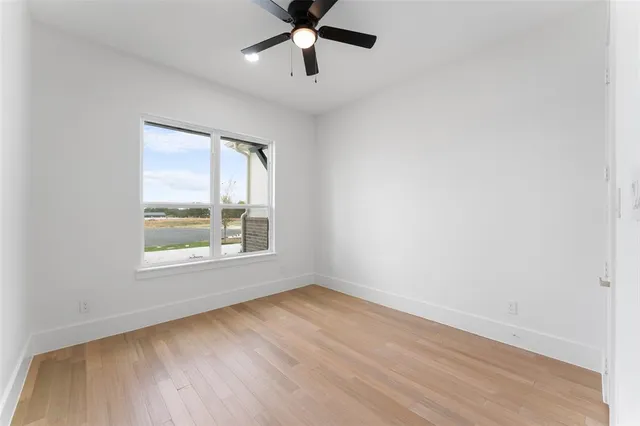 an empty room with a window and a ceiling fan