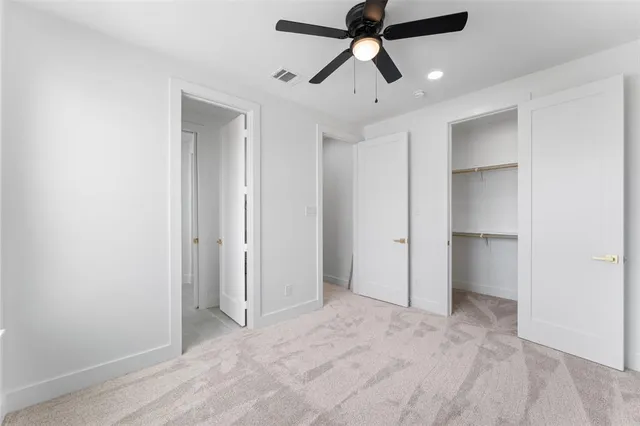 an empty room with closet and a ceiling fan