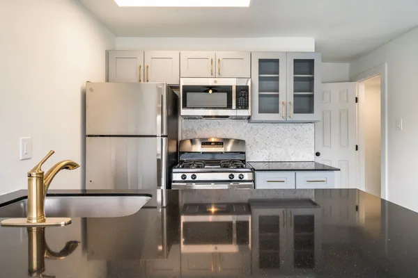 a kitchen with stainless steel appliances granite countertop a stove a refrigerator and a dining table with wooden floor