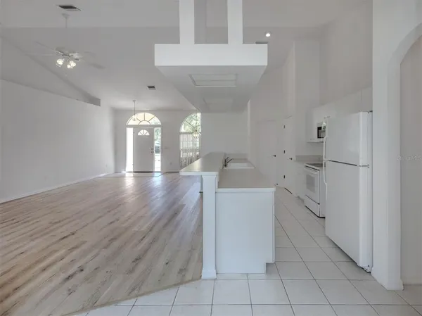 a large white kitchen with a sink and dishwasher a stove top oven with wooden floor
