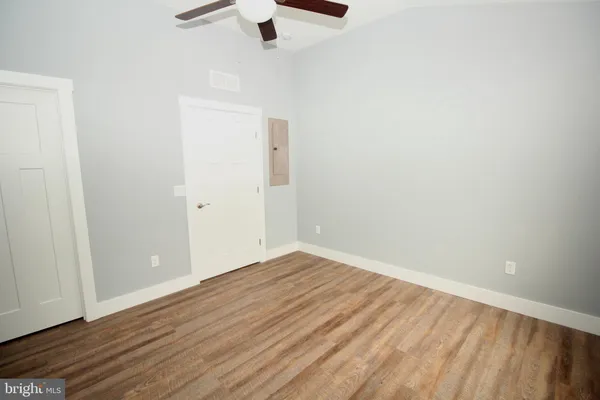 an empty room with ceiling fan and wooden floor