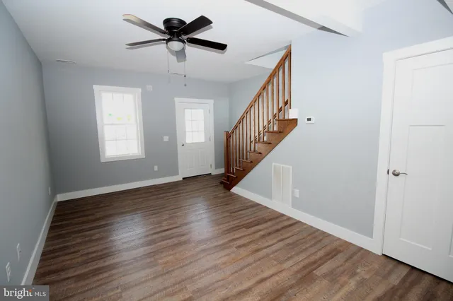 a view of empty room with wooden floor and fan