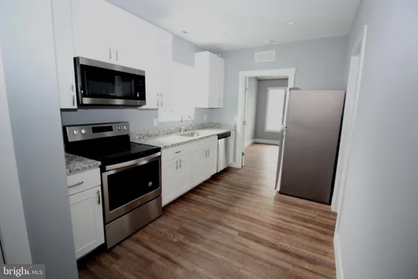 a kitchen with a refrigerator stove and wooden floor