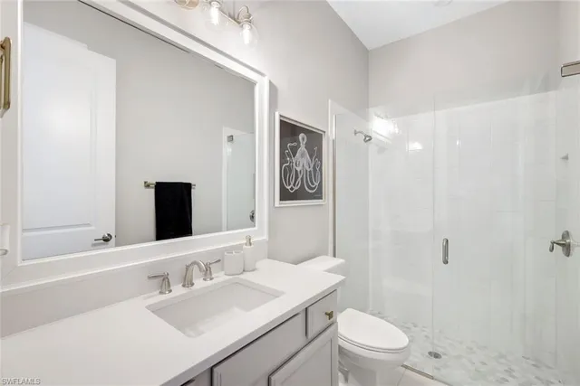 a bathroom with a sink a toilet a mirror and shower