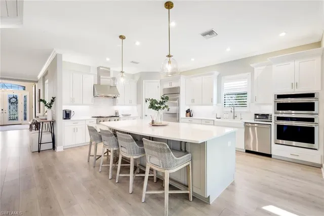 a kitchen with stainless steel appliances kitchen island granite countertop a wooden floor and white cabinets