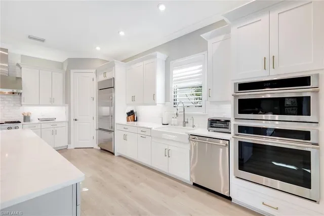 a kitchen with white cabinets stainless steel appliances and sink