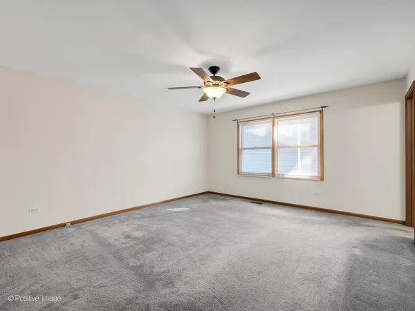 an empty room with windows and ceiling fan