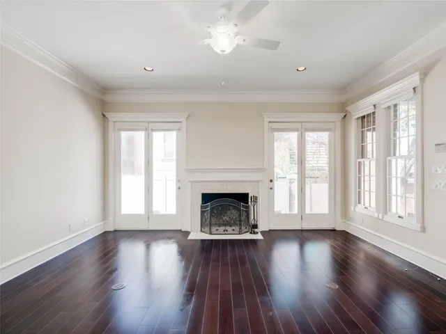 a view of an empty room with wooden floor fireplace and a window