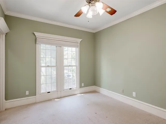 an empty room with a chandelier fan and windows