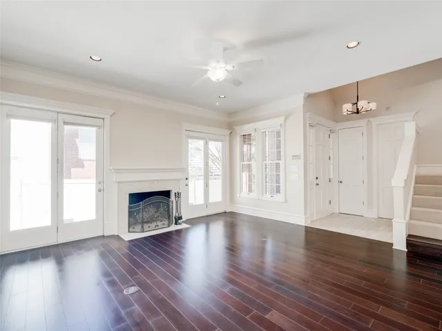 an empty room with wooden floor fireplace and windows