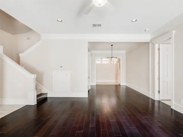 a view of an empty room with wooden floor and white walls