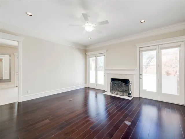 a view of an empty room with wooden floor fireplace and a window