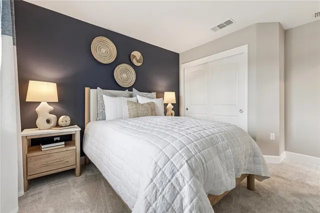 a bedroom with a bed and a lamp on dresser