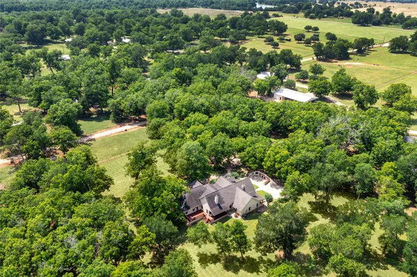 an aerial view of residential house with outdoor space and trees all around