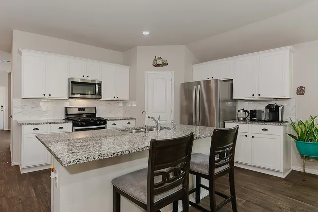 a kitchen with stainless steel appliances granite countertop a refrigerator stove microwave and sink