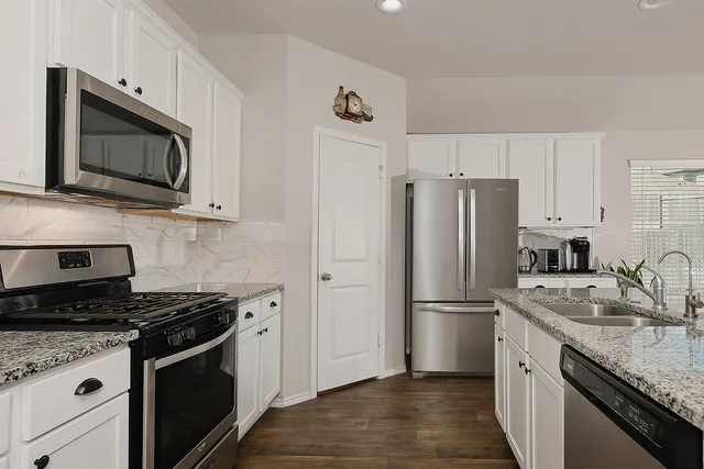 a kitchen with stainless steel appliances a stove a refrigerator a sink a stove a dining table and chairs