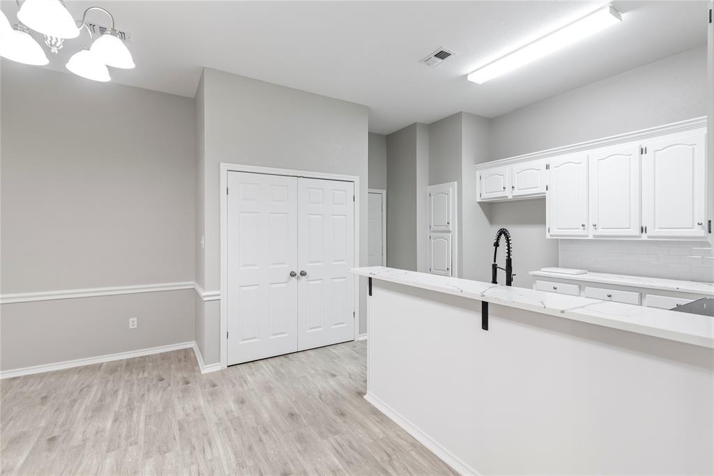 304 Moore Creek Road, Unit 300 Hurst, TX 76053 - Photo 5 of 17 Open-concept kitchen and dining area featuring light wood-finish flooring, white cabinetry, white countertops, a white subway tile backsplash, and a black gooseneck faucet