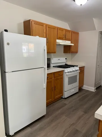 a white refrigerator freezer sitting inside of a kitchen with stainless steel appliances wooden floor