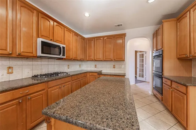a kitchen with stainless steel appliances granite countertop a stove a sink and a microwave