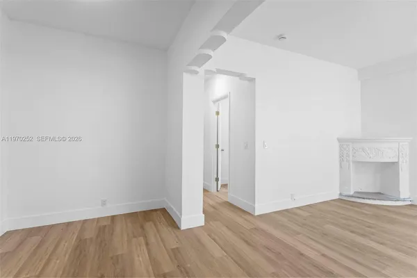 a view of an empty room with wooden floor and a fireplace