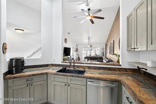 a kitchen with a sink dishwasher and white cabinets with wooden floor
