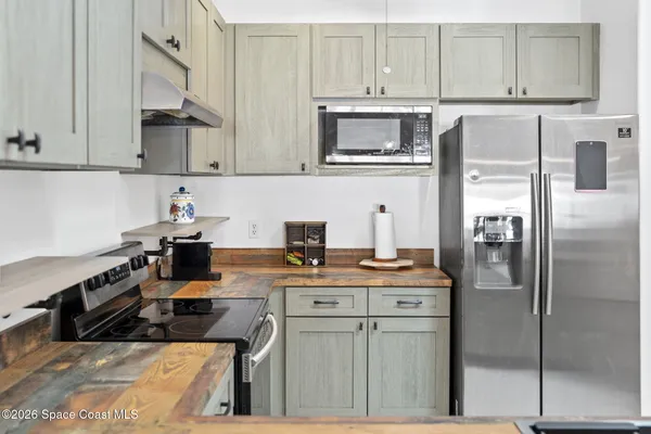 a kitchen with stainless steel appliances granite countertop a refrigerator a stove a sink and white cabinets