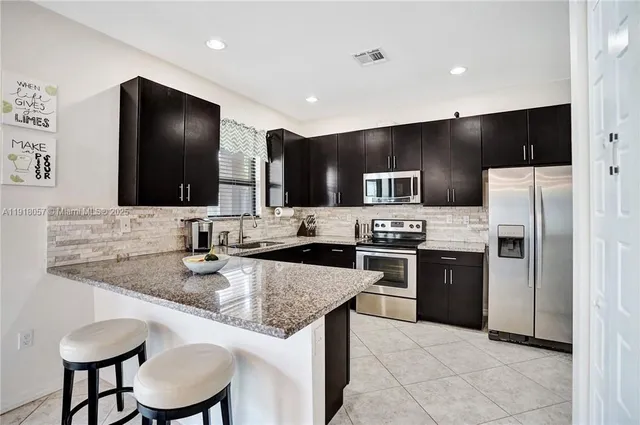 a kitchen with stainless steel appliances granite countertop a sink dishwasher a refrigerator and a stove