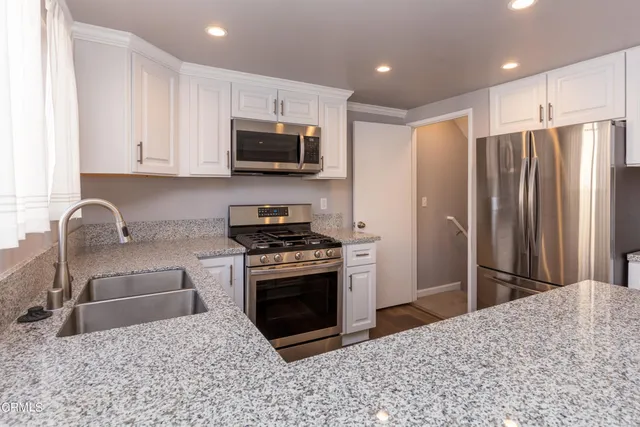 a kitchen with stainless steel appliances granite countertop a stove a refrigerator and a sink