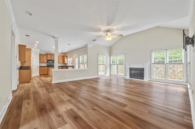 a view of an empty room with wooden floor and a kitchen