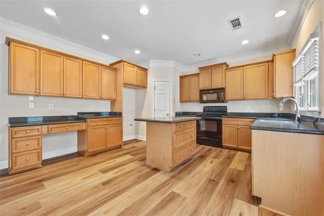 a kitchen with granite countertop wooden floors stainless steel appliances a sink and a window