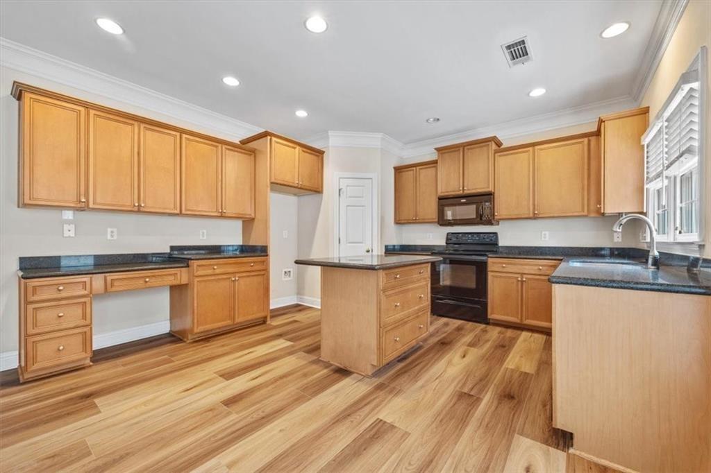 4115 Montvale Crossing Cumming, GA 30041 - Photo 12 of 40 a kitchen with granite countertop wooden floors stainless steel appliances a sink and a window