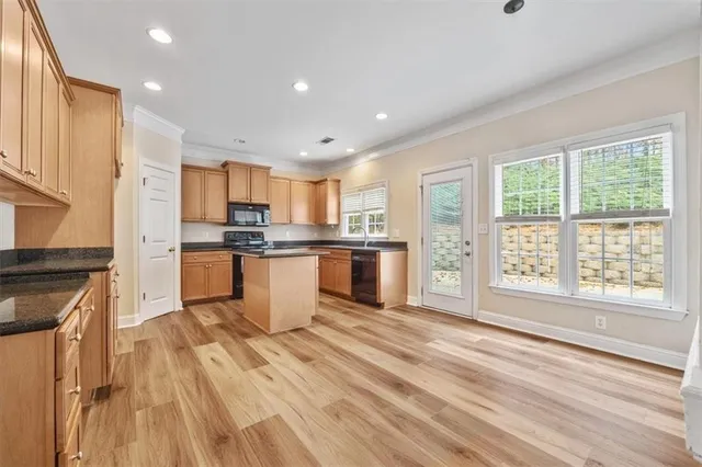 a kitchen with stainless steel appliances granite countertop a stove a sink dishwasher a refrigerator and white cabinets with wooden floor